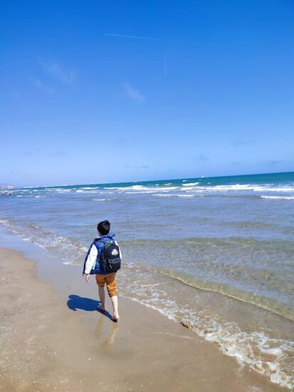 El niño paseando por la orilla del mar con los pantalones remangados